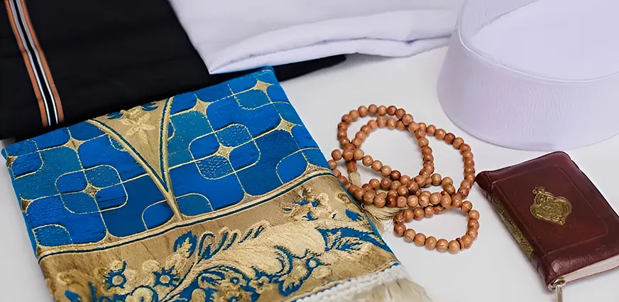 Essential prayer items for Umrah 2026 including a pocket Quran, dua book, tasbeen, lightweight prayer mat, and notebook for personal duas